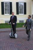 Governor Mark R. Warner riding a Segway in front of the Governor's Mansion. Date: February 2002. Citation: Governor Mark R. Warner, Press Office records, 2001-2006 (bulk 2002-2006), Accession 42460, Box 59, Disc 13. State records collection, The Library of Virginia, Richmond, Va. 23219.