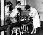 Nurses looking through microscopes. Date: 1962.