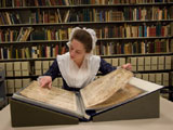 Interpreter Melanie Collins reads an eighteenth-century ledger of a Yorktown merchant. Collection: Arlington County Public Library