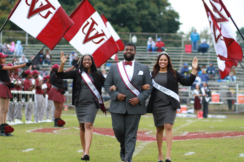 Three Virginia Union University students walking on a football field in formal attire.