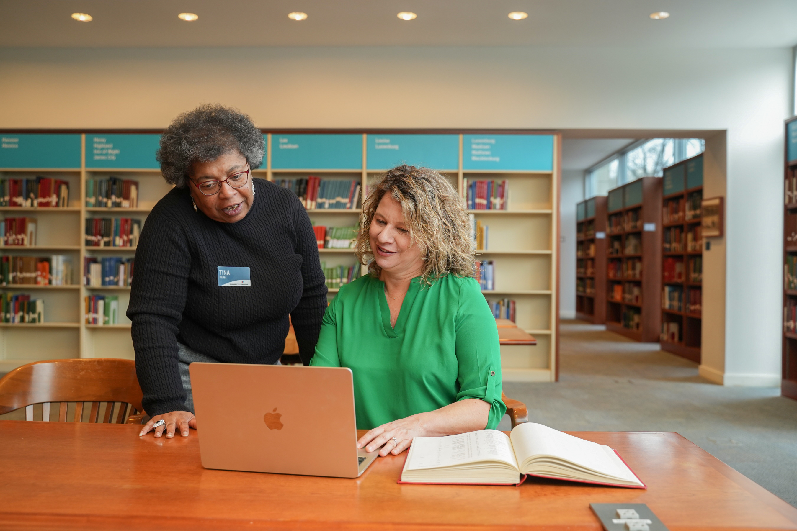 Librarian helping author research on a computer
