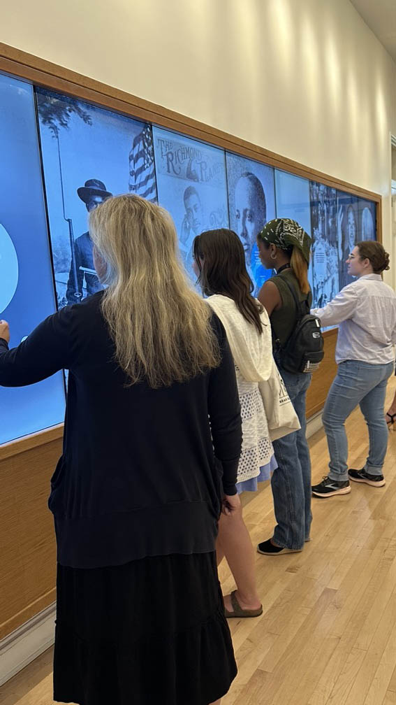 Four people stand in front of interactive digital displays