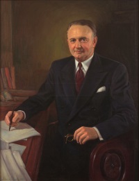 oil portrait of a white man in a suit and tie sitting at a desk