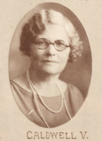 Headshot of a white woman with glasses wearing 1920s attire.