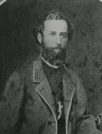 White man with a beard wearing 19th century attire.