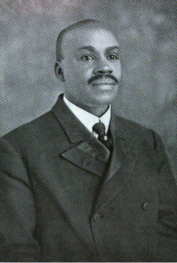 Headshot of an African American man with a mustache wearing a suit and tie.