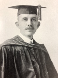 Headshot of a white man wearing a graduation cap and gown.