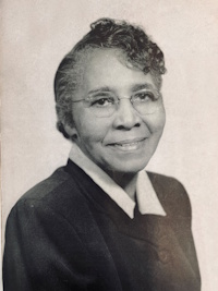African American woman with glasses wearing mid-20th century attire.