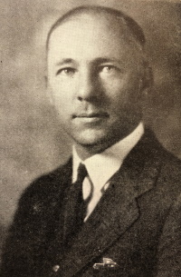 Headshot of a white man wearing a mid-20th century suit.