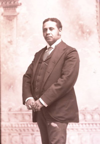 Studio photograph of an African American man wearing a suit and tie.