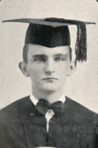 Yearbook photo of a young white man wearing a graduation cap and gown.