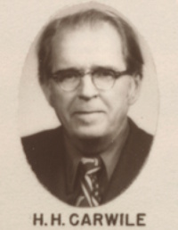 Headshot of a white man with glasses wearing mid-20th century attire.