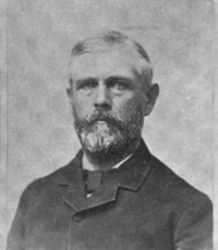Headshot of a white man with a beard wearing late 19th century attire.