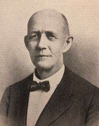 Headshot of a white man wearing early 20th century attire.