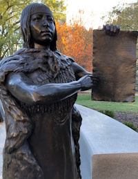 Statue of a Native American woman pointing to a document in her hand.