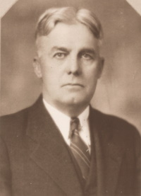 Headshot of a white man wearing a suit and tie.