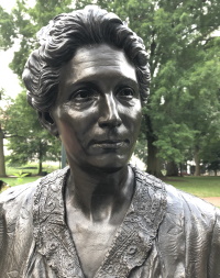 Bronze statue of a white woman wearing mid-20th century attire.