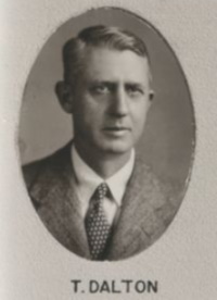 Headshot of a white man wearing a mid-20th century suit and tie.