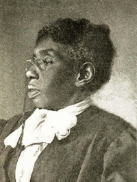 Side view of an African American woman with glasses wearing early 20th century attire.