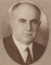 Headshot of a white man wearing a suit and tie.