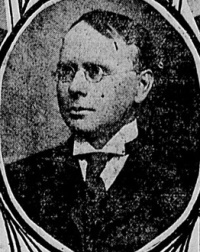 Newspaper photograph of a white man wearing glasses and early 20th century attire.