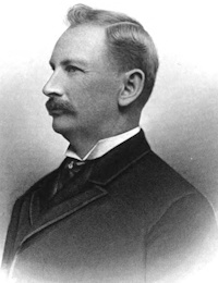 Side view portrait of a white man with a mustache wearing late 19th century attire.