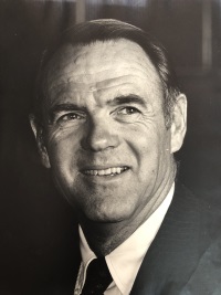 Headshot of a white man wearing a suit and tie.
