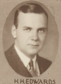 Headshot of a white man wearing a mid-20th century suit and tie.