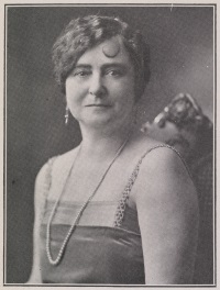 Headshot of a white woman wearing 1920s-era attire.