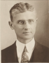 Headshot of a white man with glasses wearing early 20th century attire.