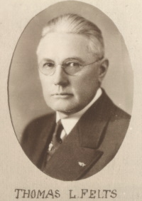 Headshot of a white man with glasses wearing early 20th century attire.