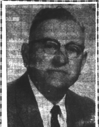 Newspaper photograph of a white man with glasses wearing a mid-20th century suit and tie.