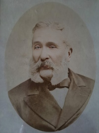 African American man with mustache and mutton chop sideburns wearing late 19th century attire.