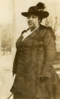 African American woman wearing an early 20th century hat and coat.