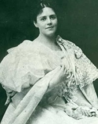 Young white woman wearing an elaborate 19th century white dress.