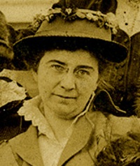 Close up of a white woman wearing 1910s era hat and jacket.