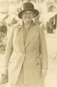 Candid photograph of a white woman wearing 1920s era hat and jacket.