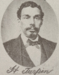 Headshot of an African American man with a mustache and goatee wearing late 19th century attire.