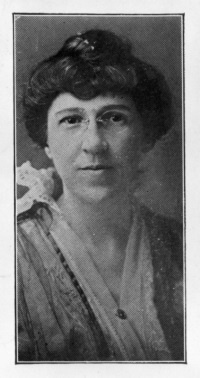 Headshot of a white woman with glasses wearing late 19th century attire.