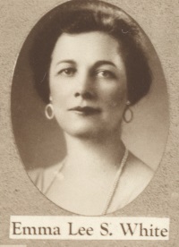 Headshot of a white woman wearing earrings and a pearl necklace.