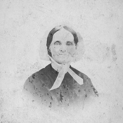 Faded black and white photograph of a woman with dark hair tucked under a white bonnet. She is wearing a dark top.