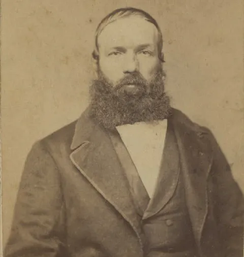 Sepia-toned portrait of a bearded man in a formal suit.