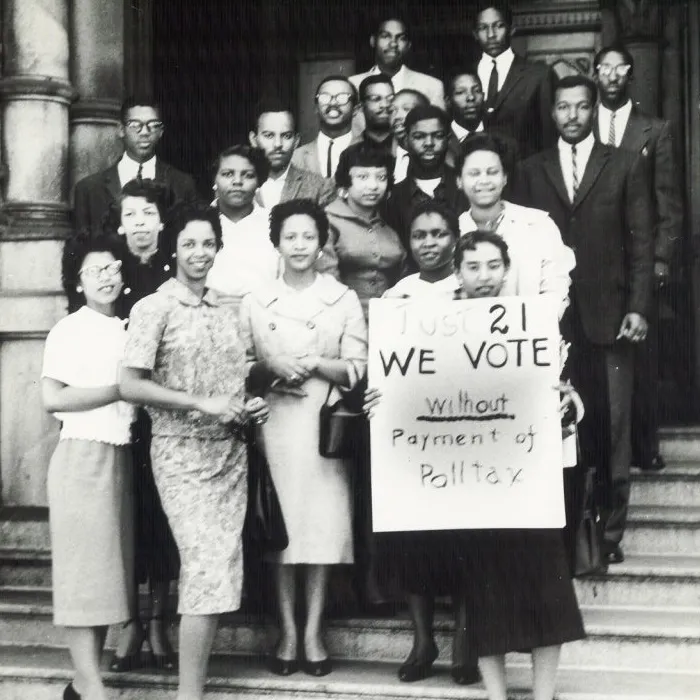  group of African American young adults standing on stairs in front of a building with one holding a sign that reads Just 21 We vote without payment of poll tax