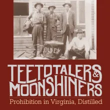 black and white photograph of three men standing and one man sitting by a liquor still 