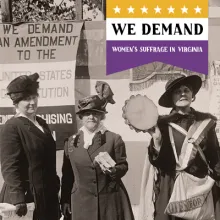three women wearing hats and 1910s attire standing at an outdoors booth and holding stacks of leaflets about woman suffrage